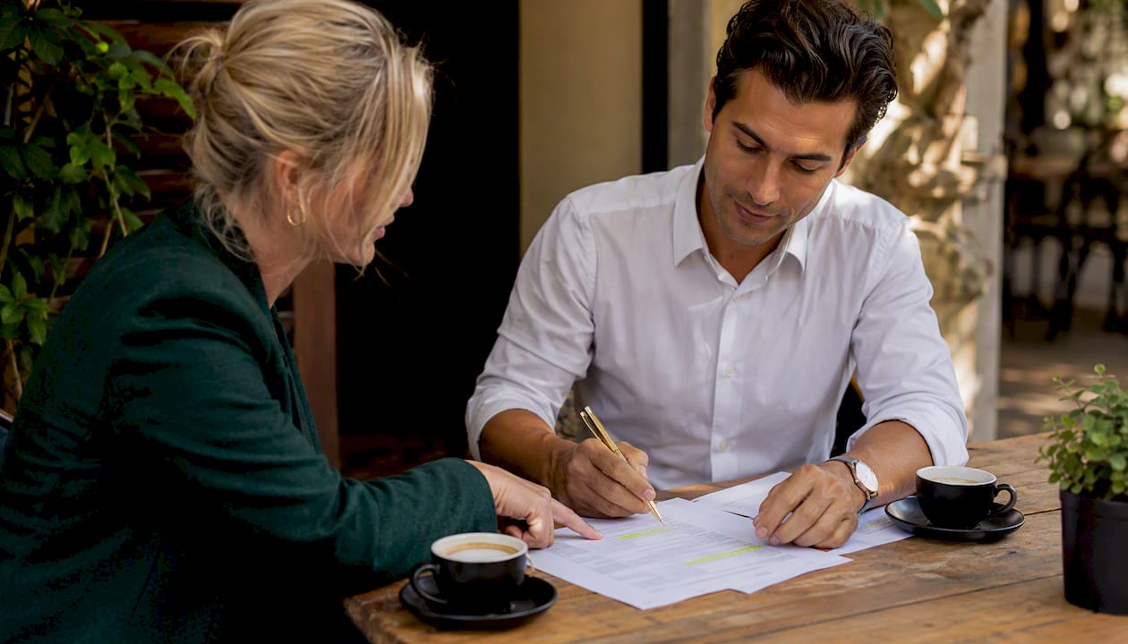 Hands discussing real estate contract clauses over coffee